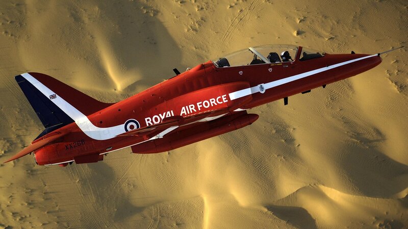 Red jet flying over desert