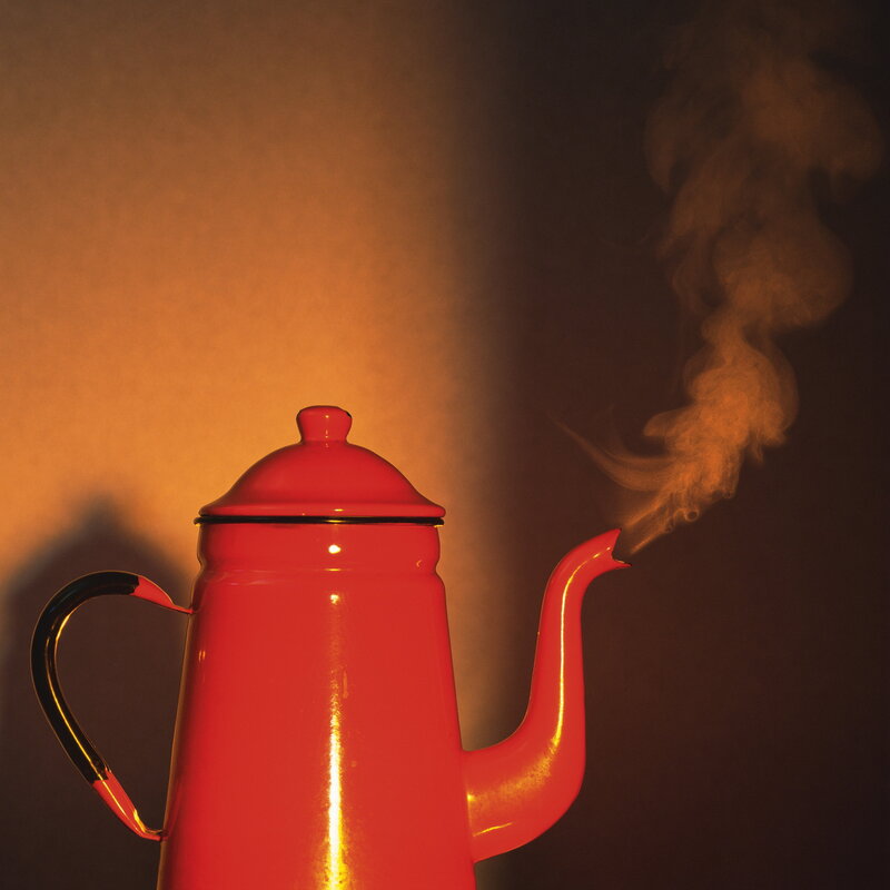 Red kettle steaming in warm light