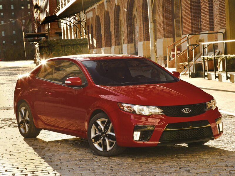 Red Kia Forte Coupe on cobblestones