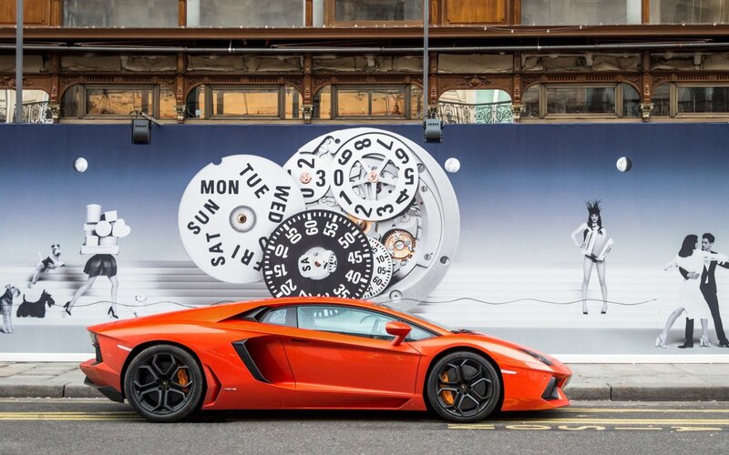 Red Lamborghini in front of clock mural