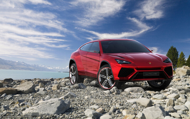 Red Lamborghini Urus on rocky shore