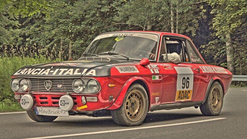 Red Lancia rally car on forest road
