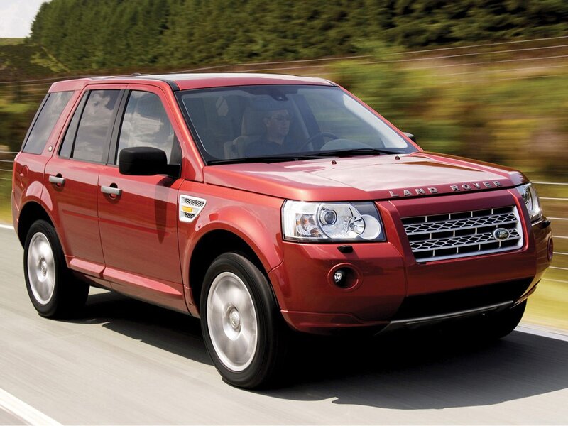 Red Land Rover driving on road