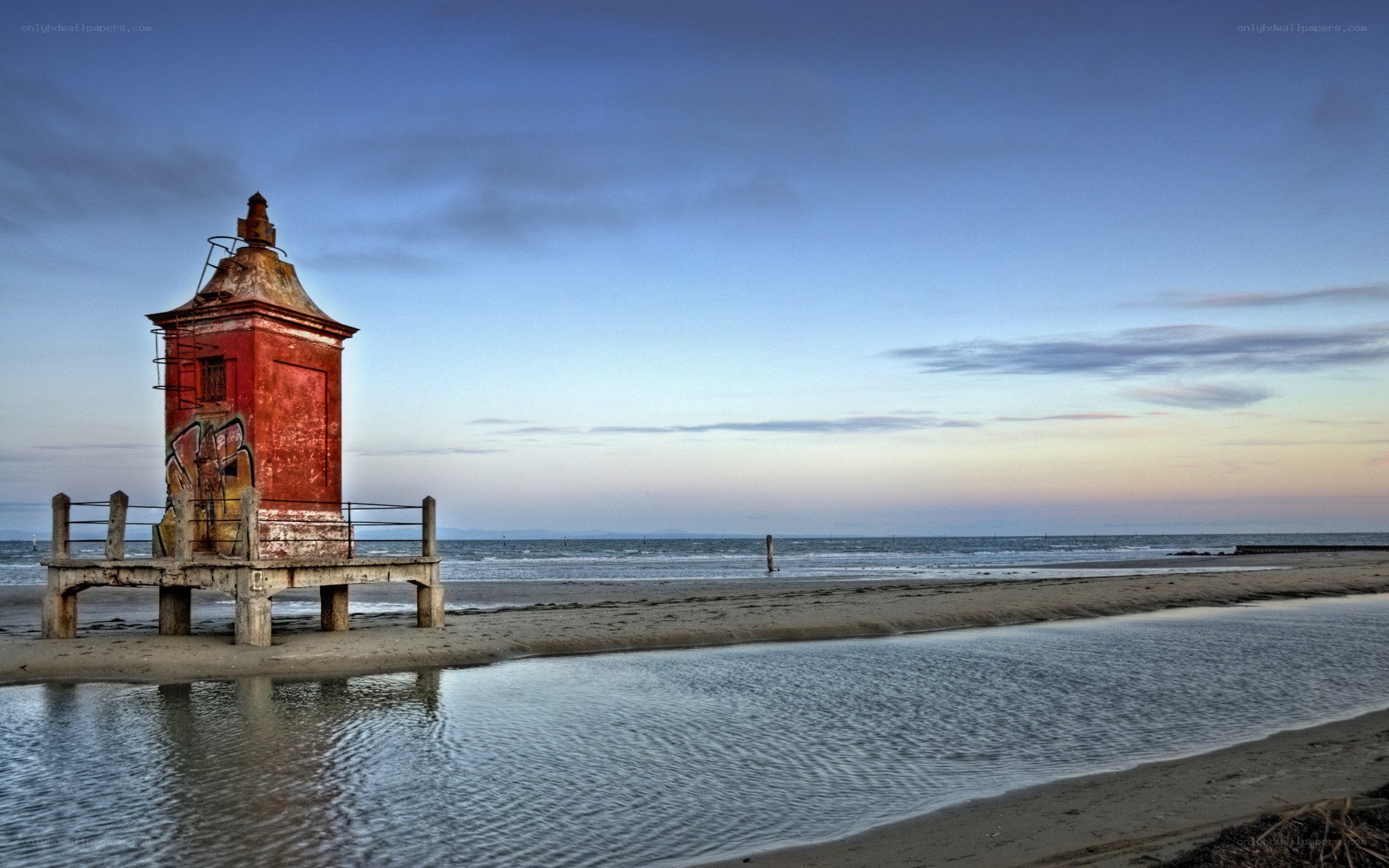 Red lighthouse on a beach at dusk