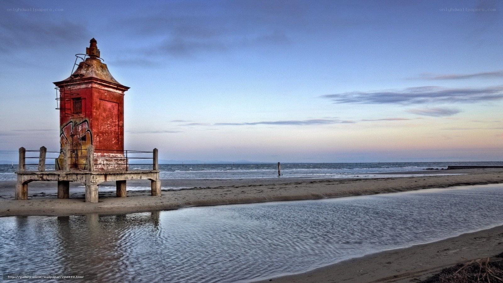 Red lighthouse on beach at dusk