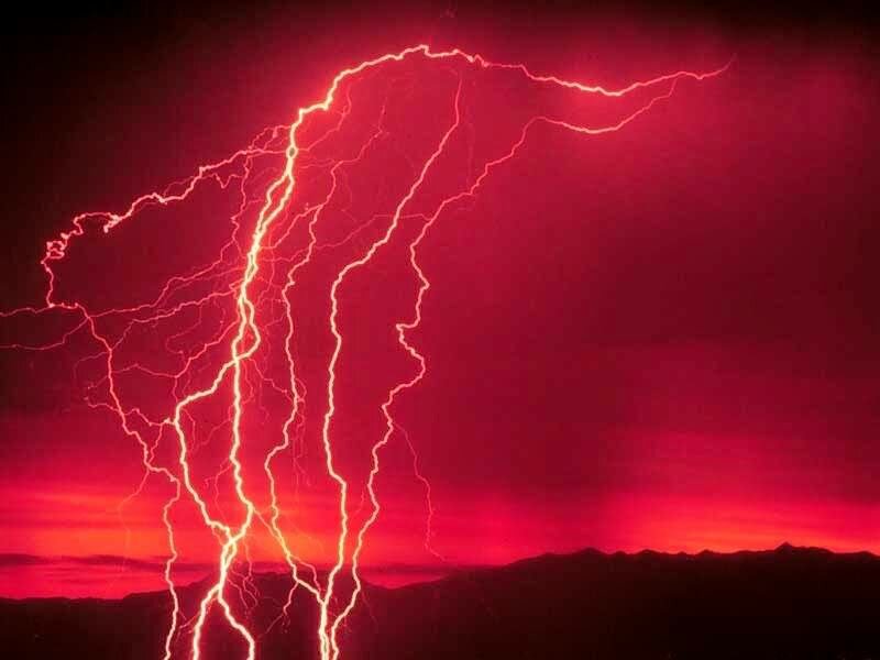 Red lightning storm over mountains