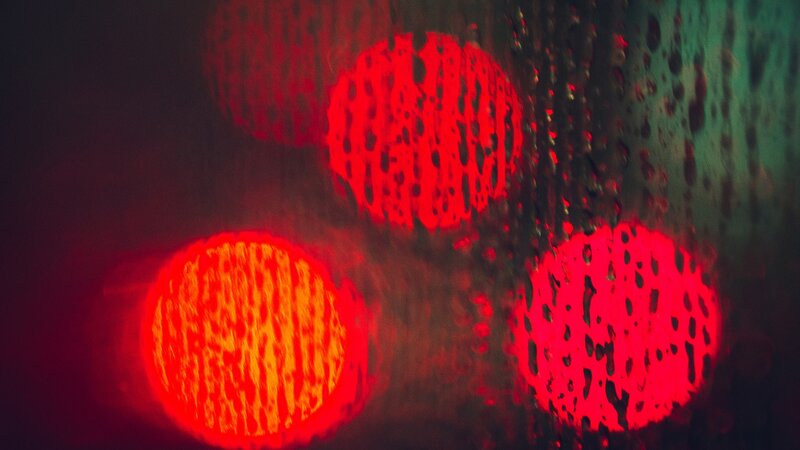 Red lights through rain-streaked glass