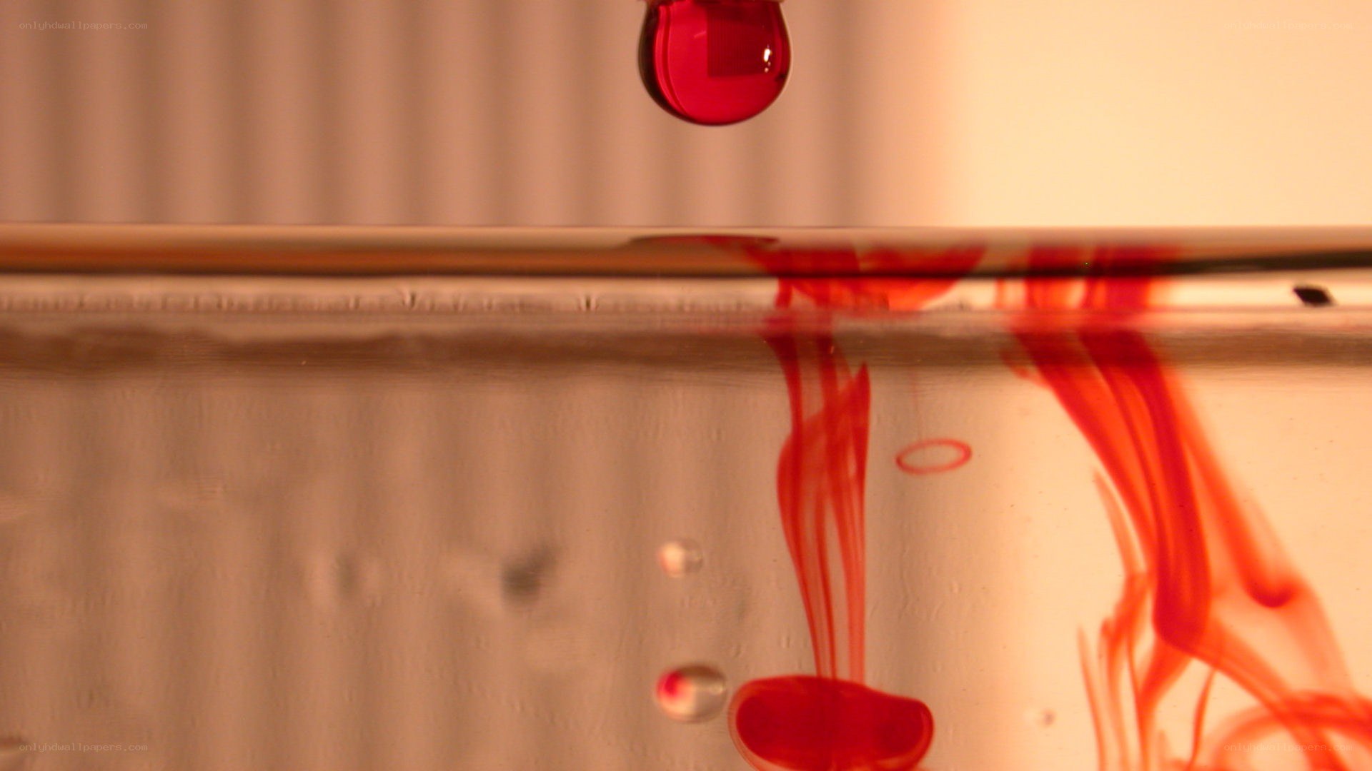 Red liquid dripping into water