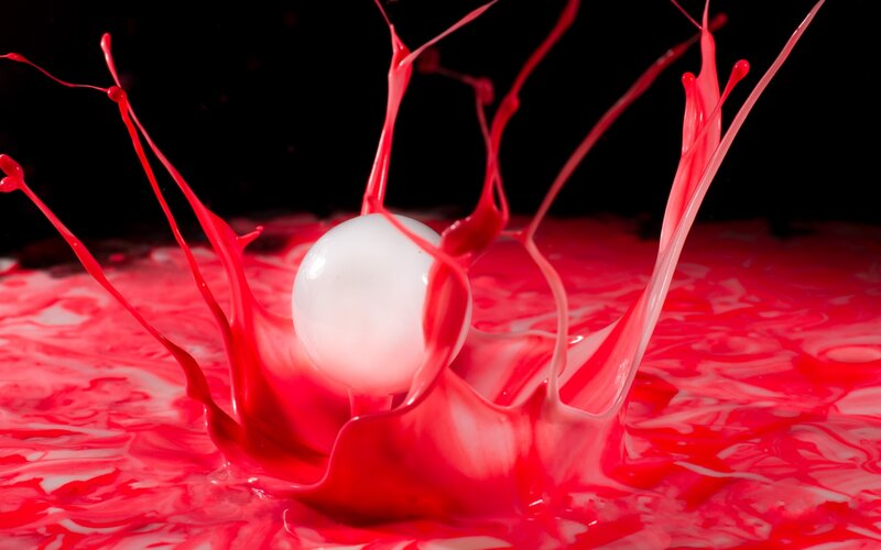 red liquid splashing around white ball