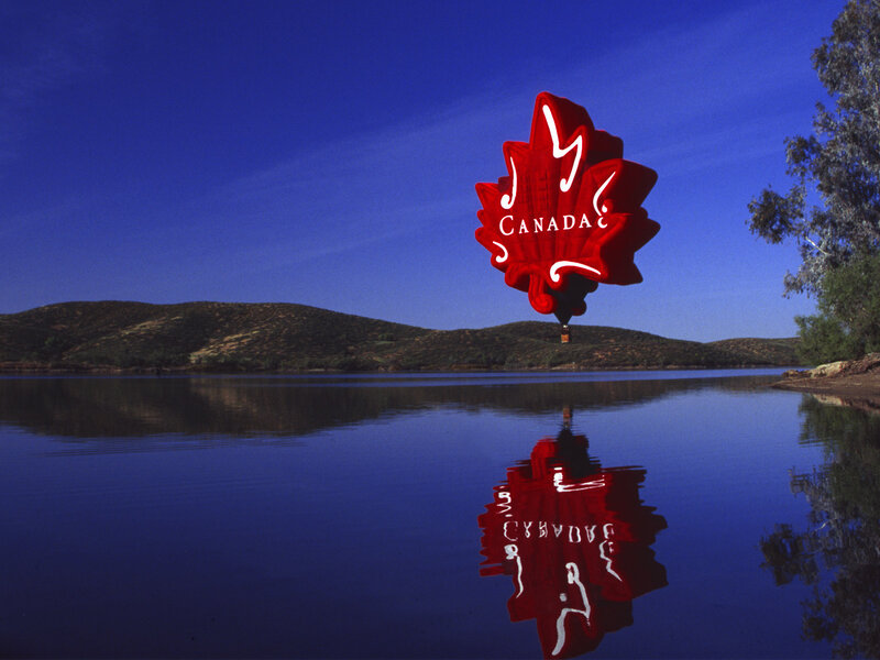 Red maple leaf balloon over lake