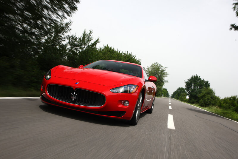 Red Maserati driving on road