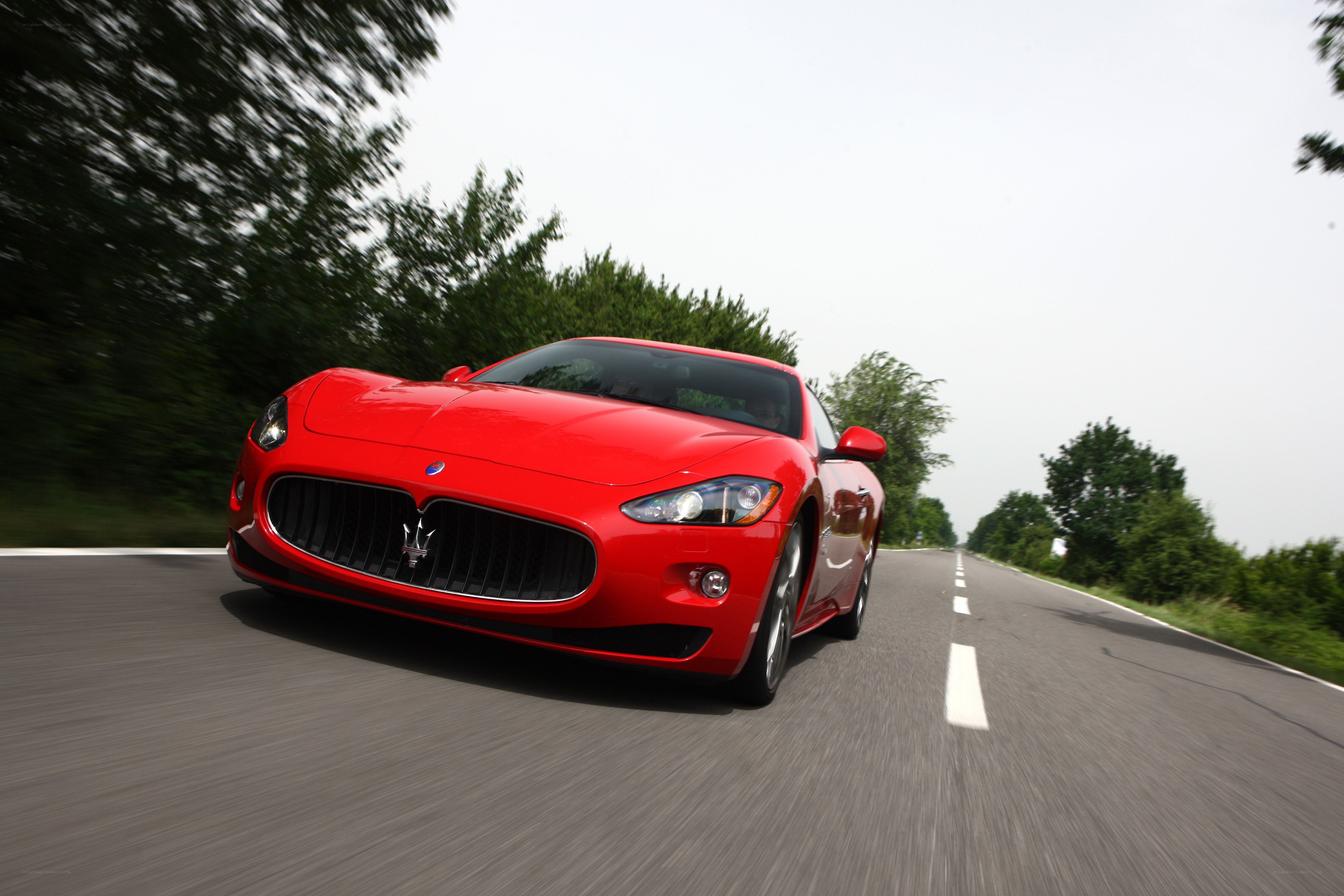 Red Maserati driving on road