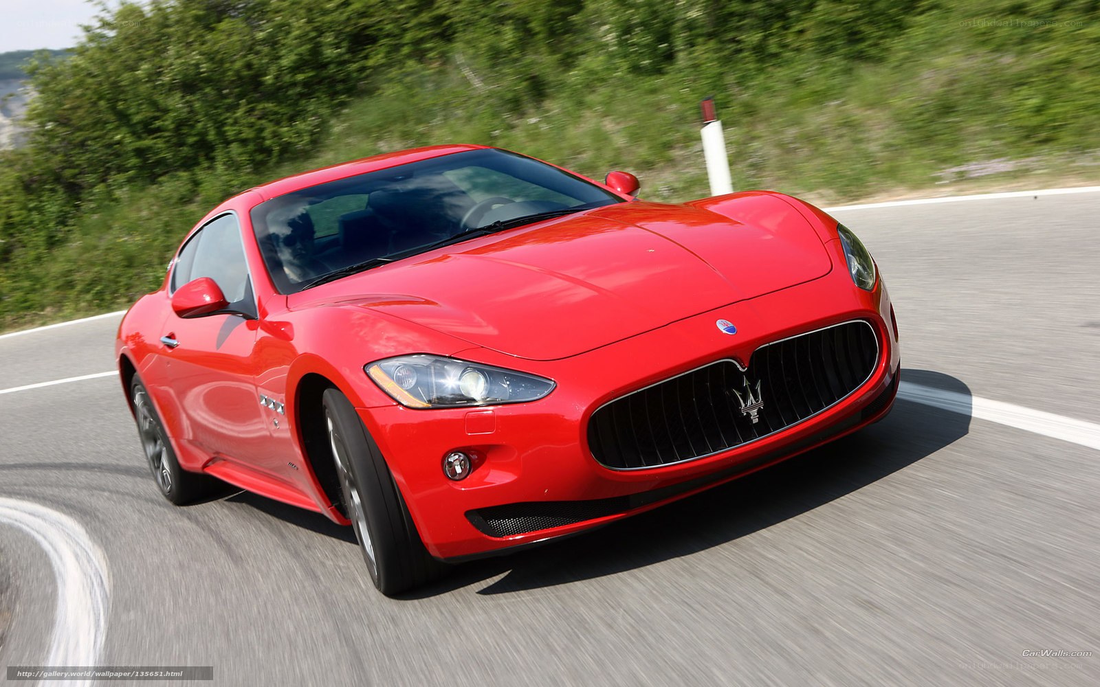 Red Maserati driving on road