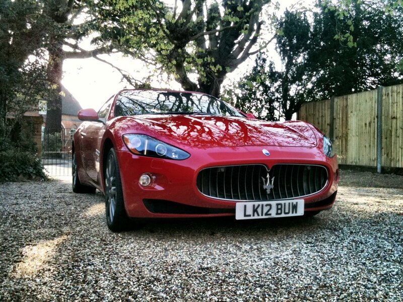 Red Maserati parked on gravel