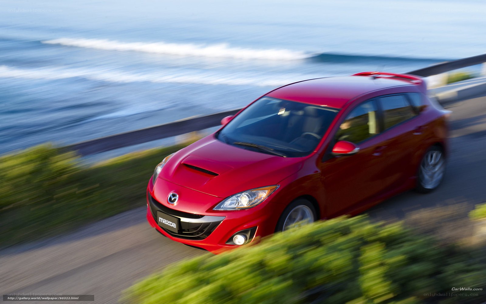 Red Mazda 3 driving by the coast