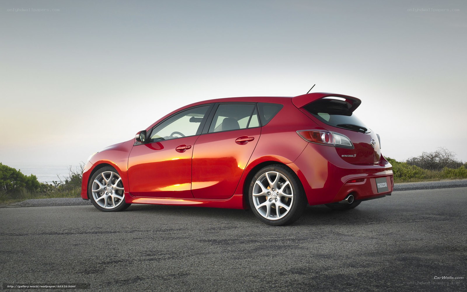 Red Mazda 3 hatchback on road