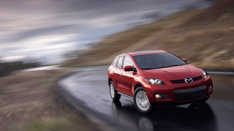 Red Mazda CX-7 driving on wet road