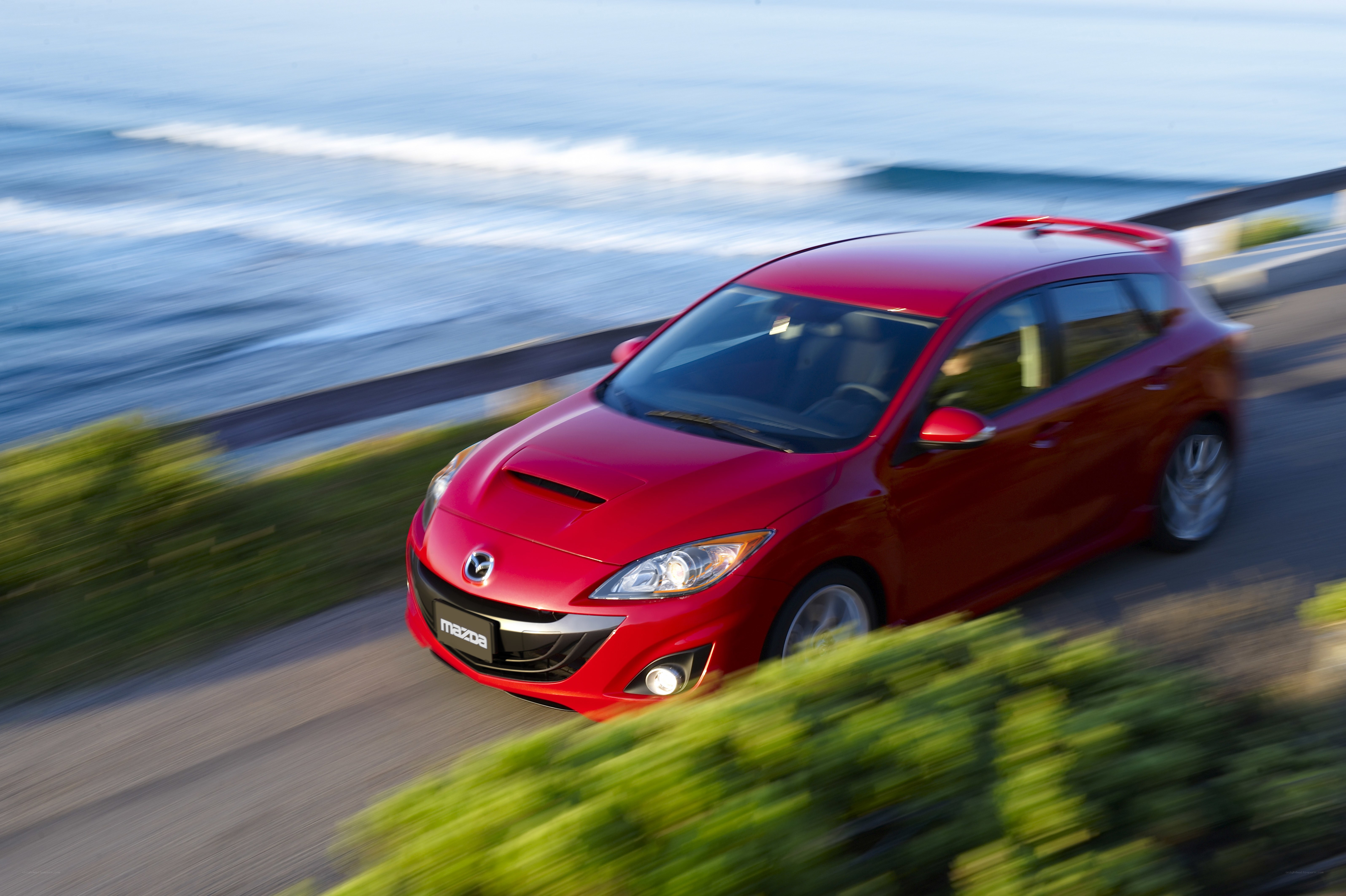 Red Mazda driving by the ocean