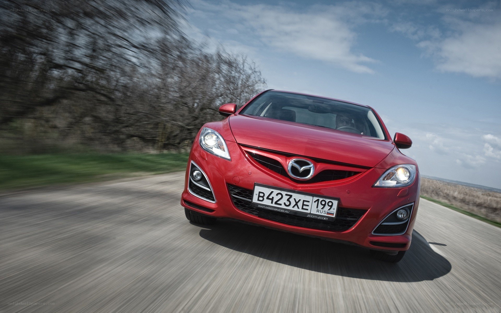 Red Mazda driving on road