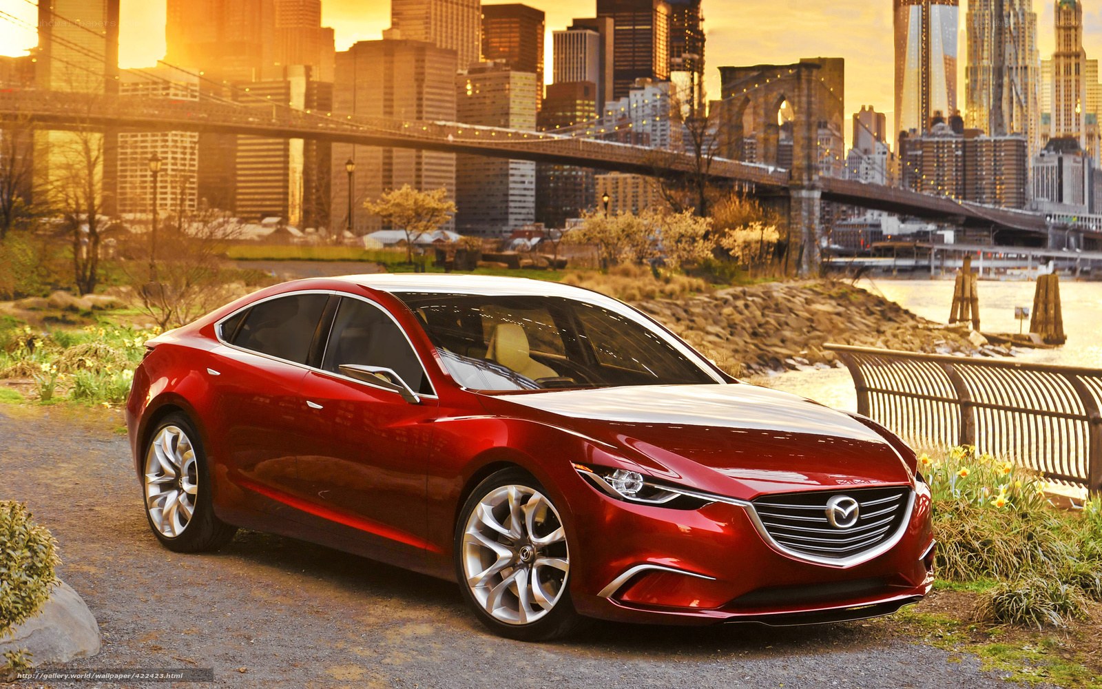 Red Mazda sedan by city bridge