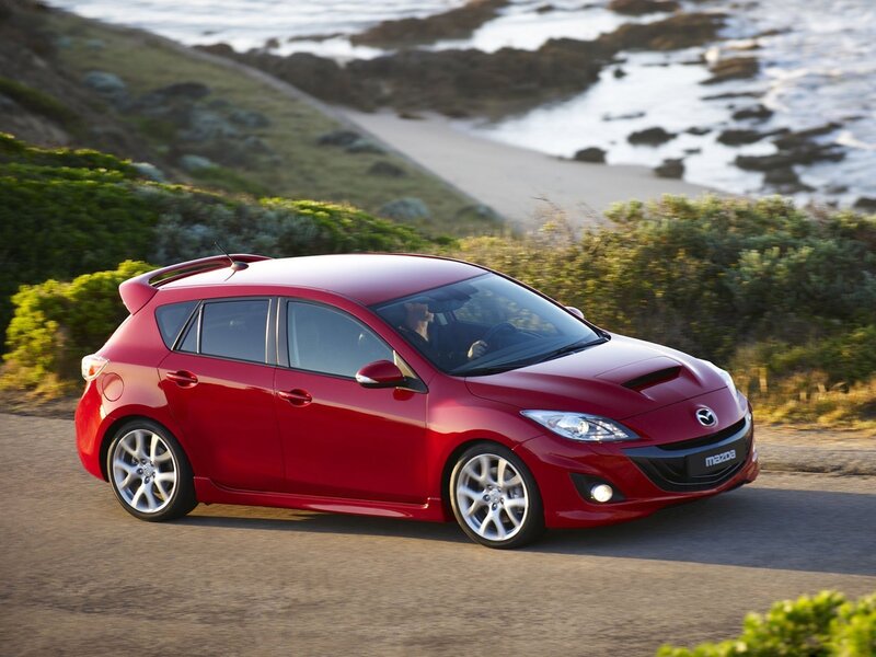 Red Mazda3 driving on coastal road