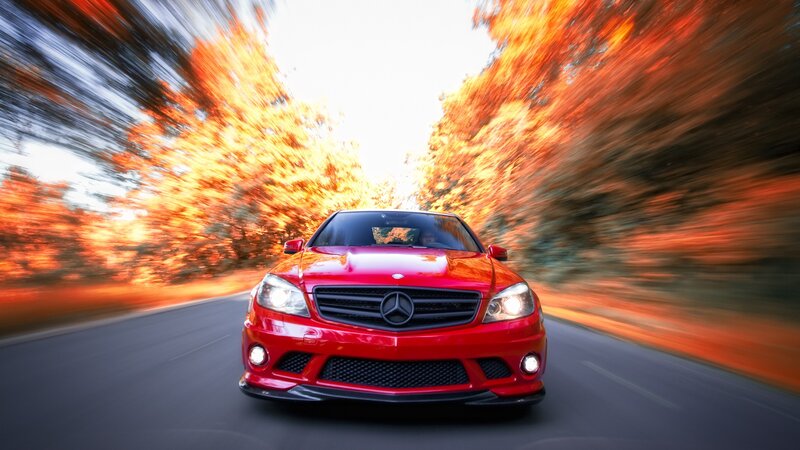 Red Mercedes driving on autumn road