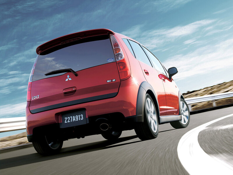 Red Mitsubishi Colt driving on road