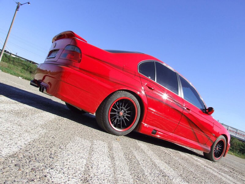 Red modified sedan on gravel