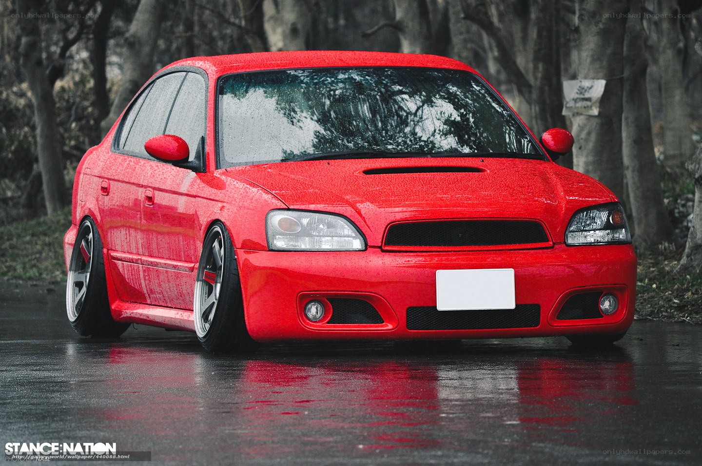 red modified sedan on wet road