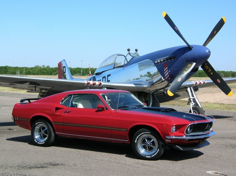 Red muscle car and vintage plane