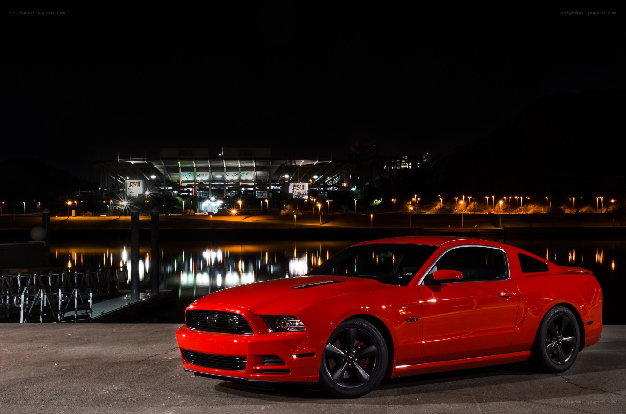 Red Mustang at night by stadium