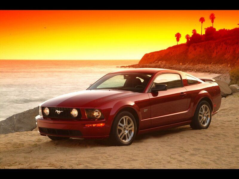 Red Mustang on beach at sunset