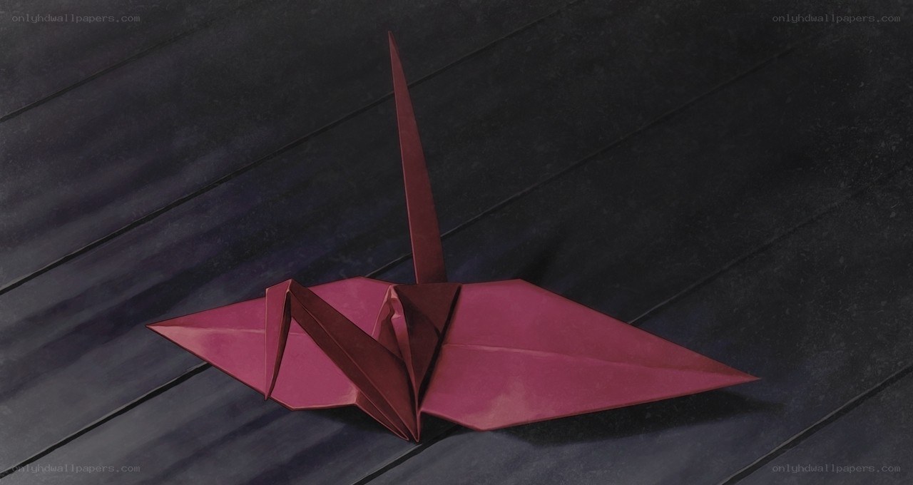 Red origami crane on dark surface