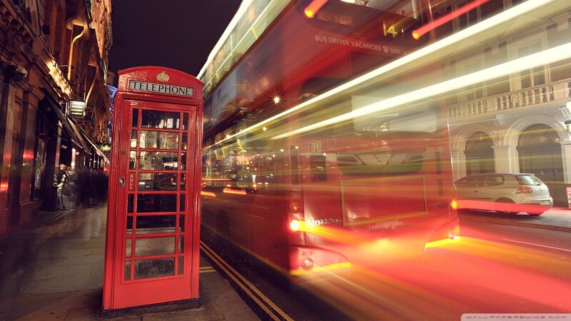 Red phone booth and bus at night
