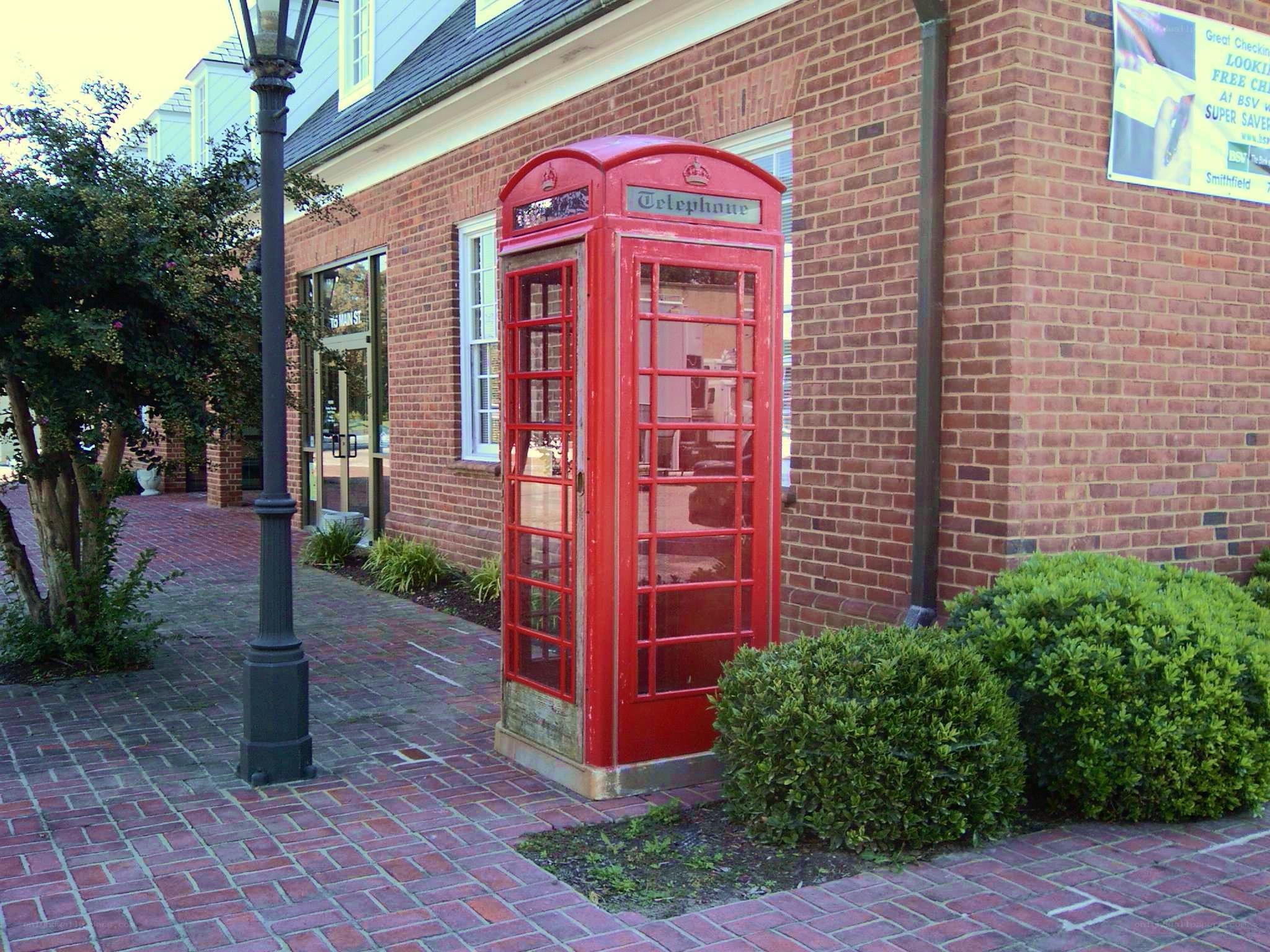 Red phone booth on brick sidewalk