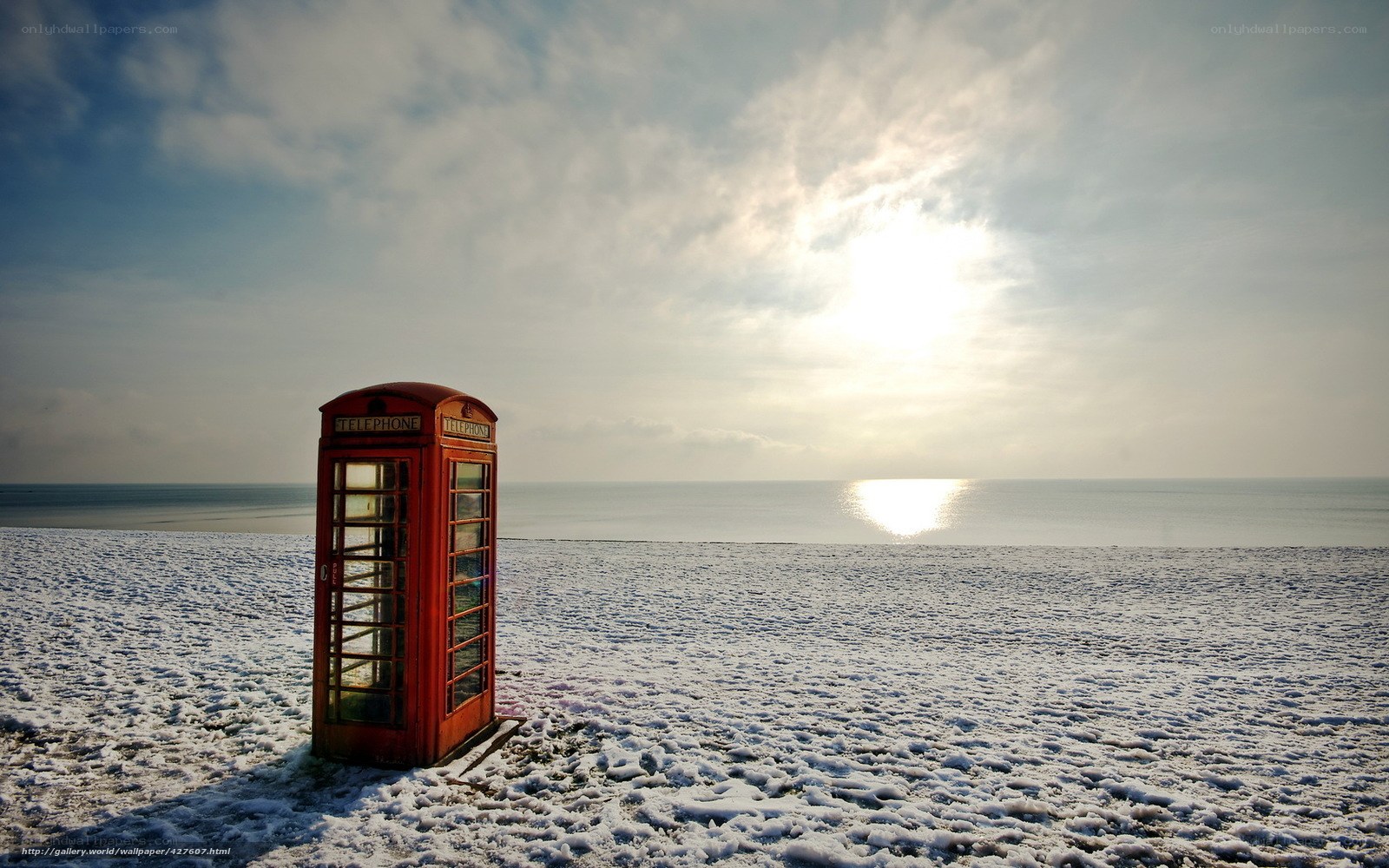 Red phone booth on snowy beach