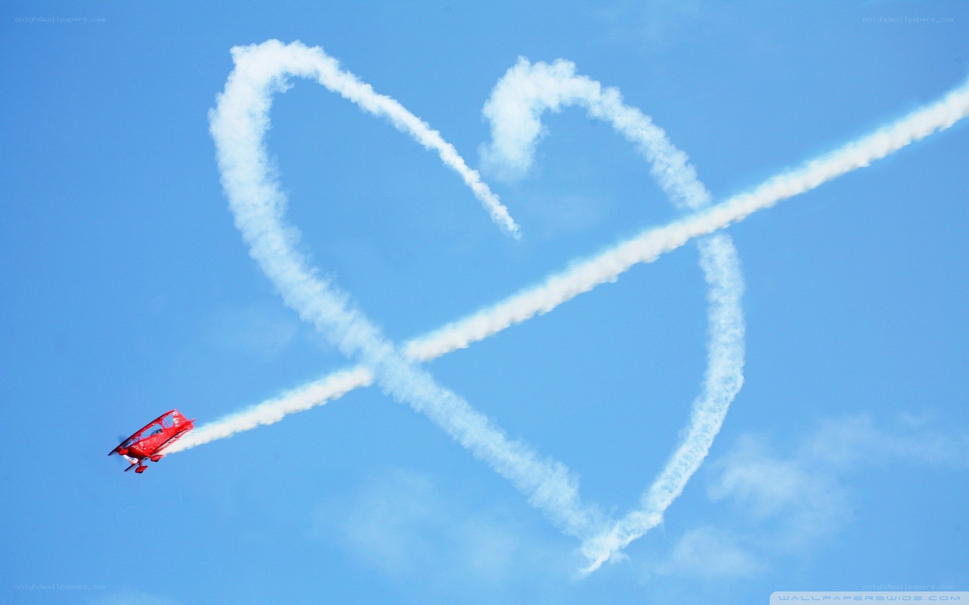 Red plane drawing heart in sky