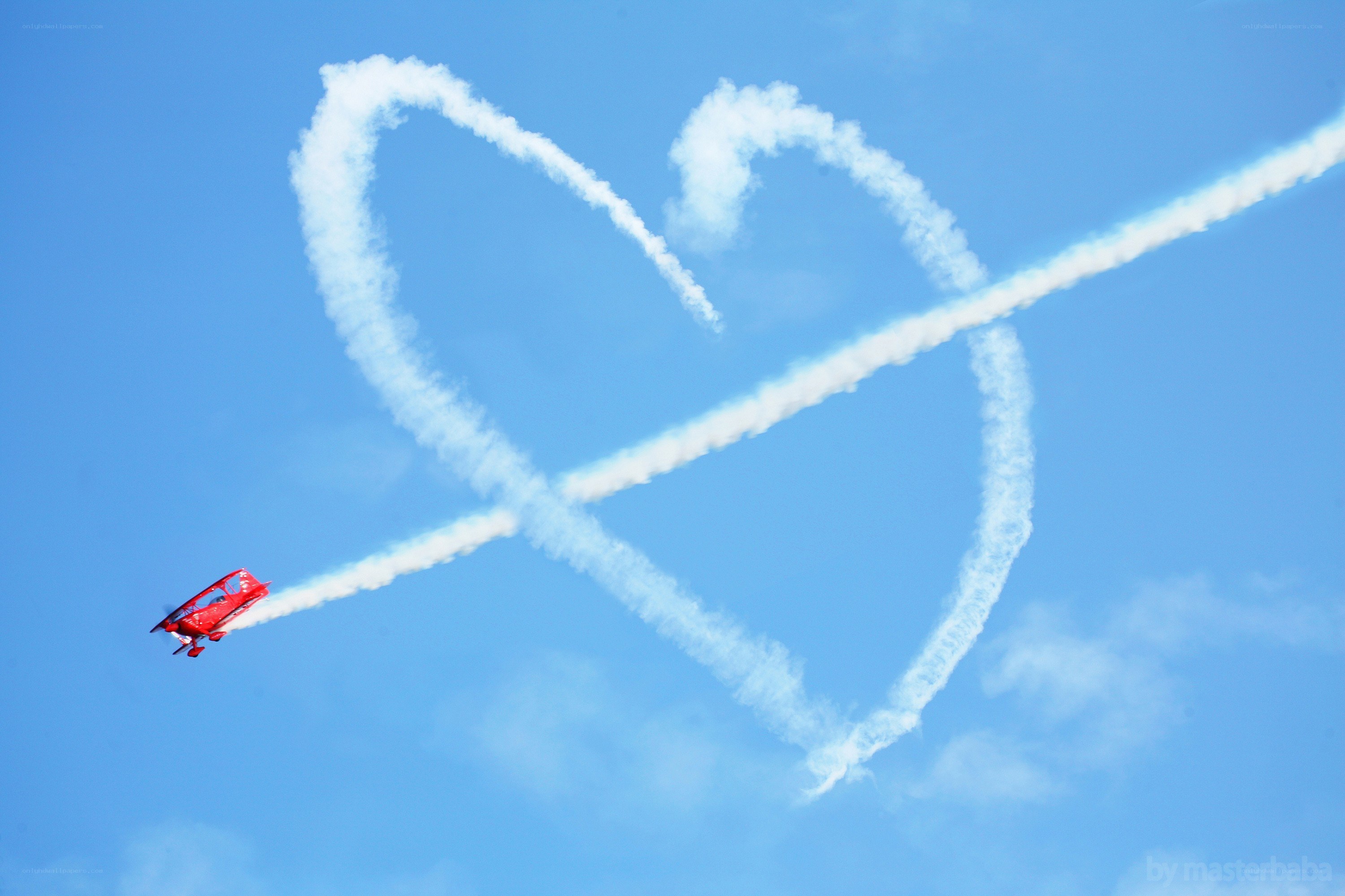Red plane drawing heart in sky