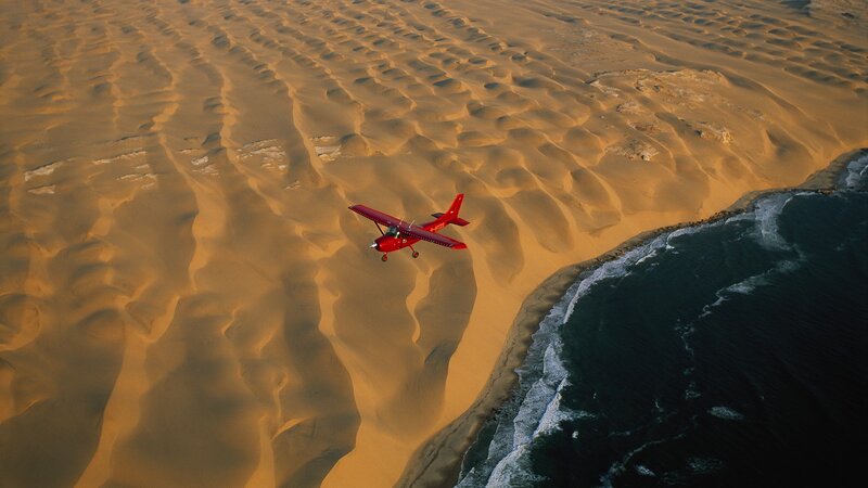 Red plane over desert coast