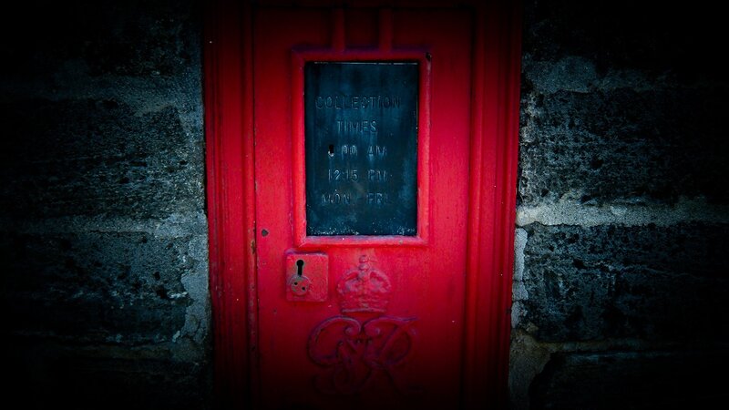 Red post box on stone wall