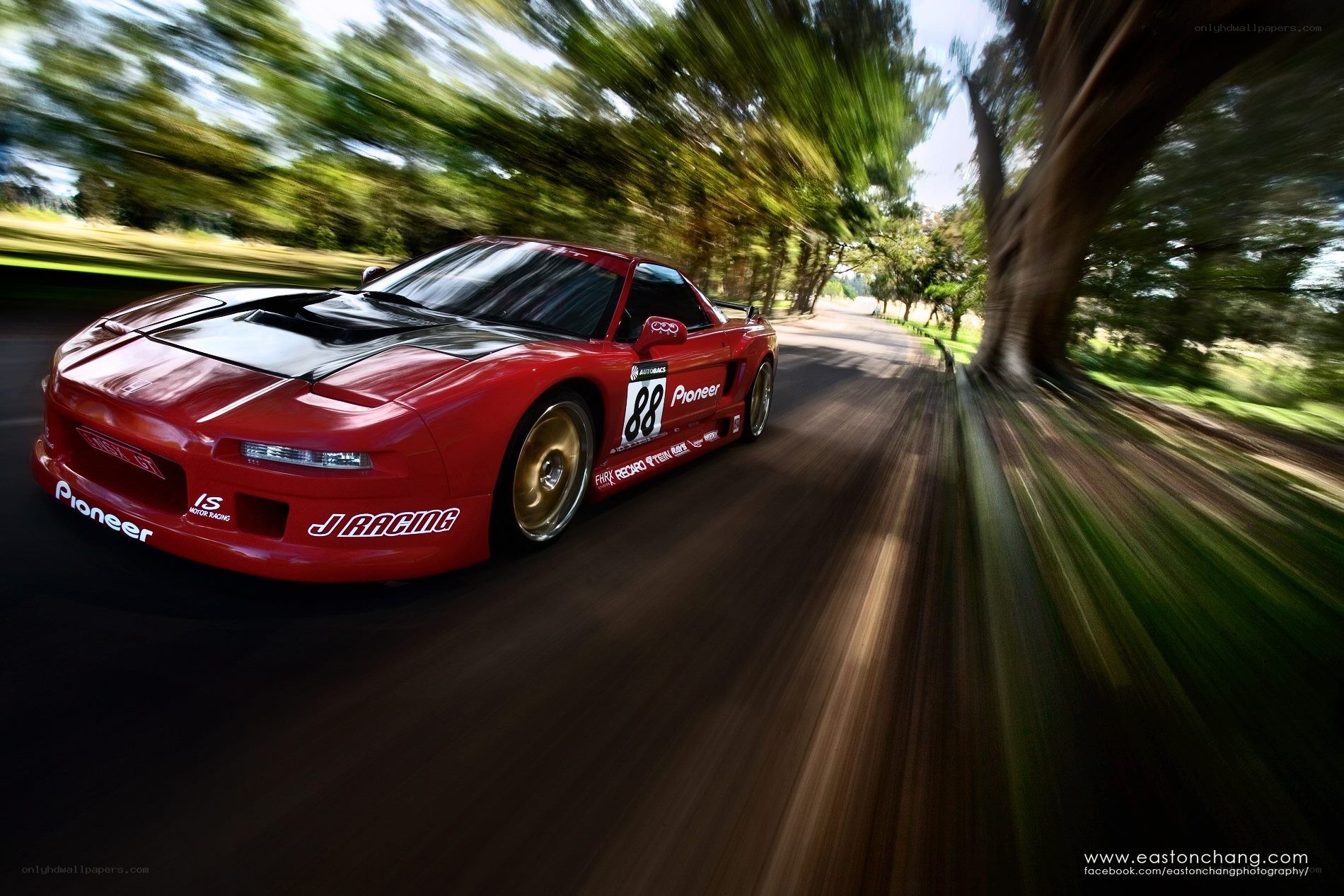 Red race car on a tree-lined road