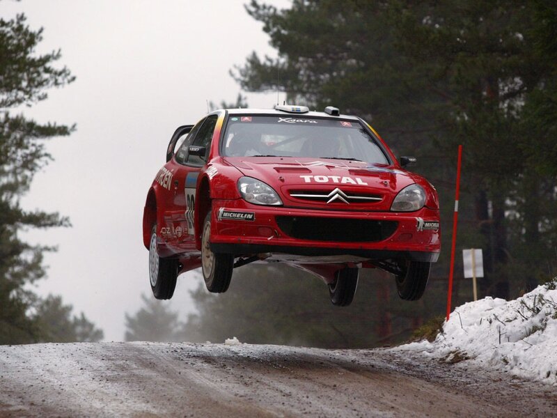 Red rally car in mid-air jump