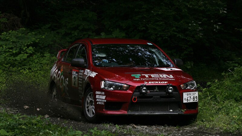 Red rally car on forest track