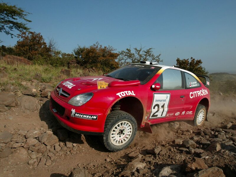 Red rally car on rocky terrain