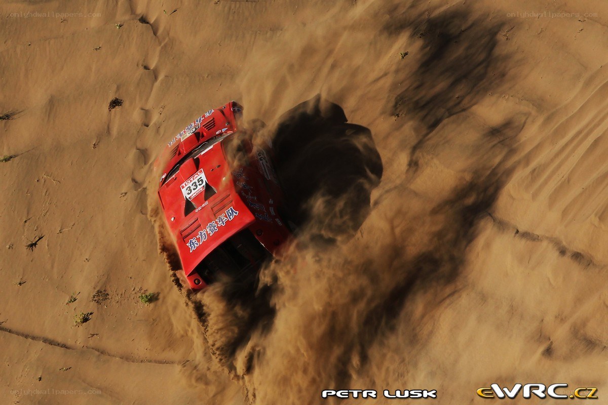 Red rally car on sand dune