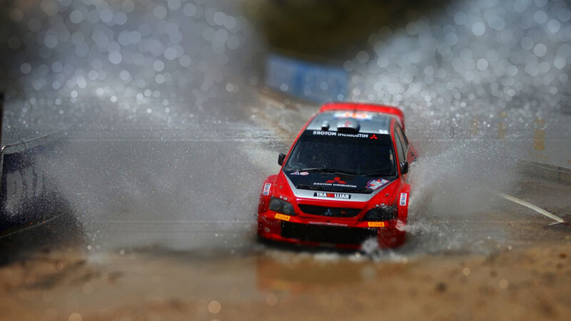 Red rally car splashing water