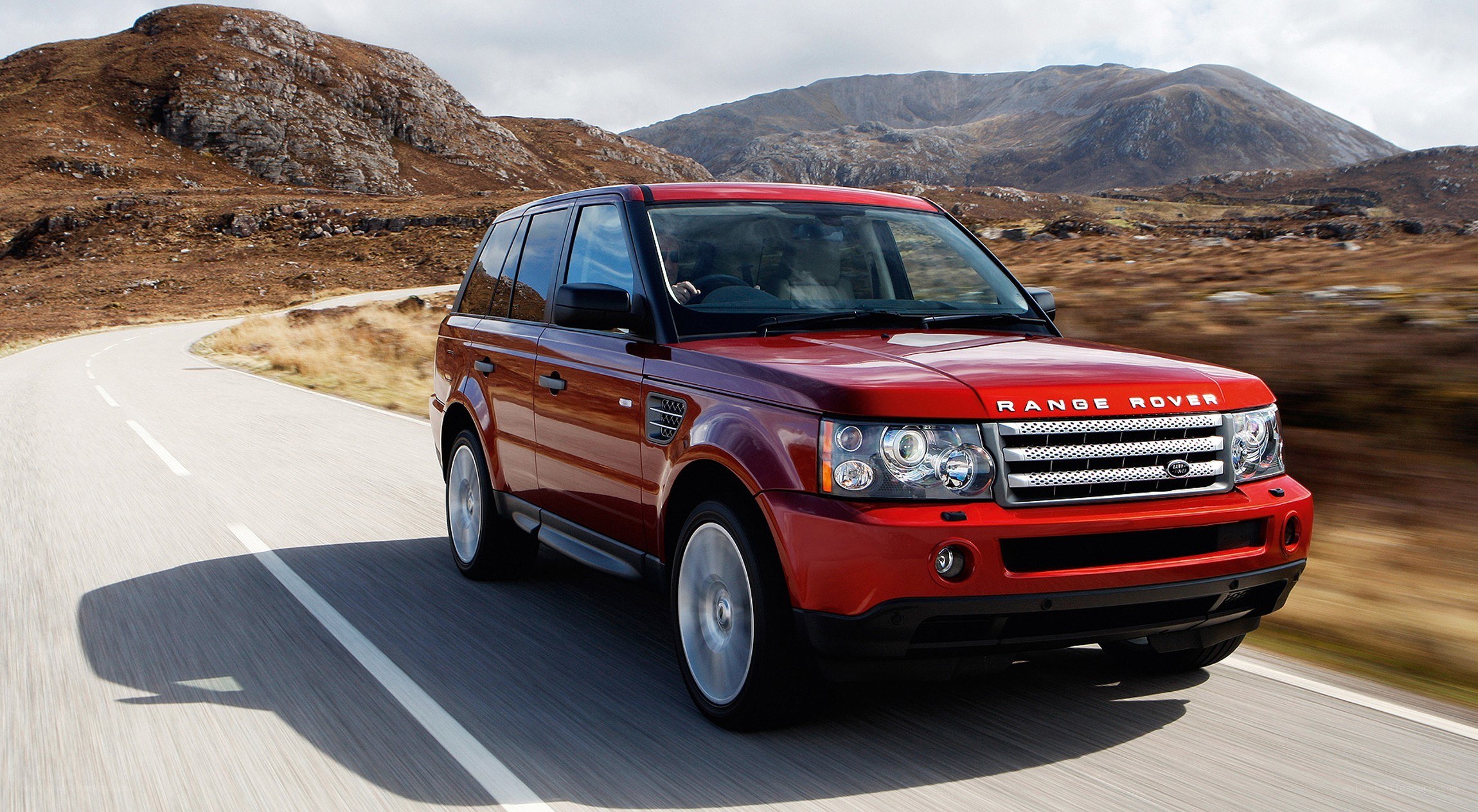Red Range Rover driving on a road