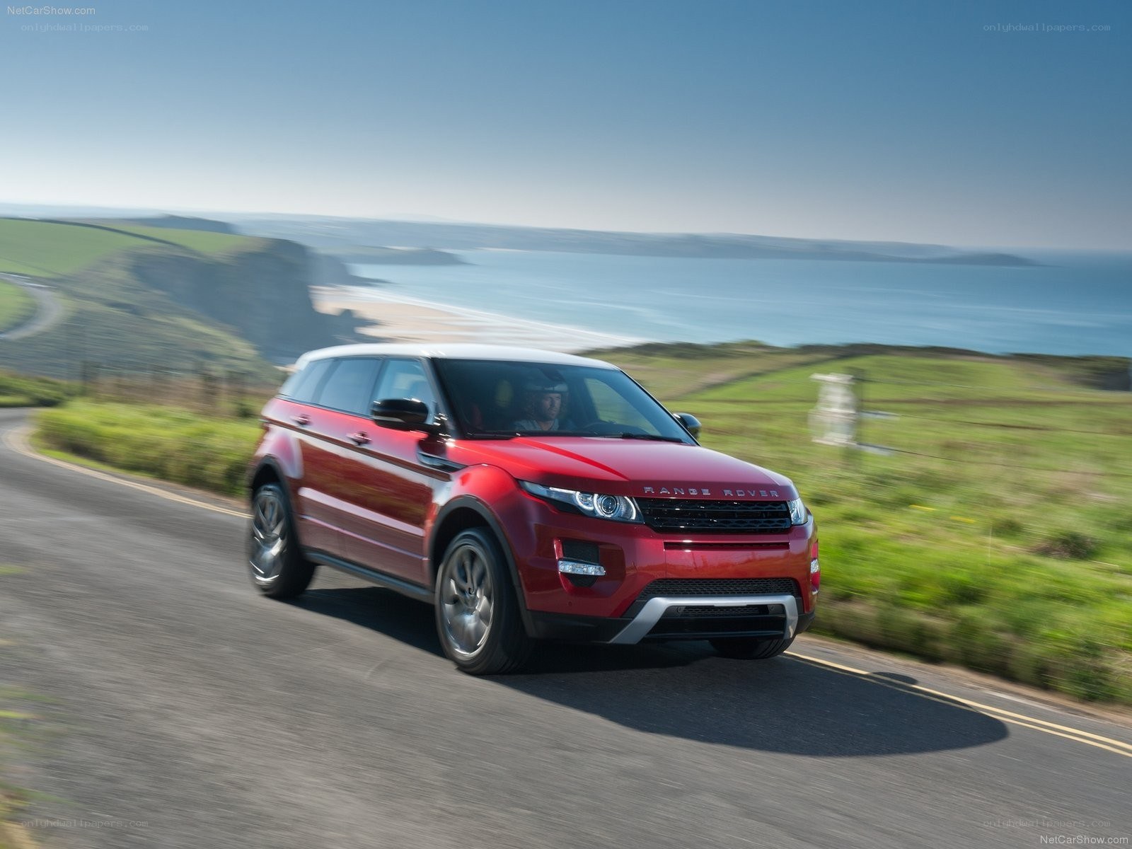 Red Range Rover driving on coastal road
