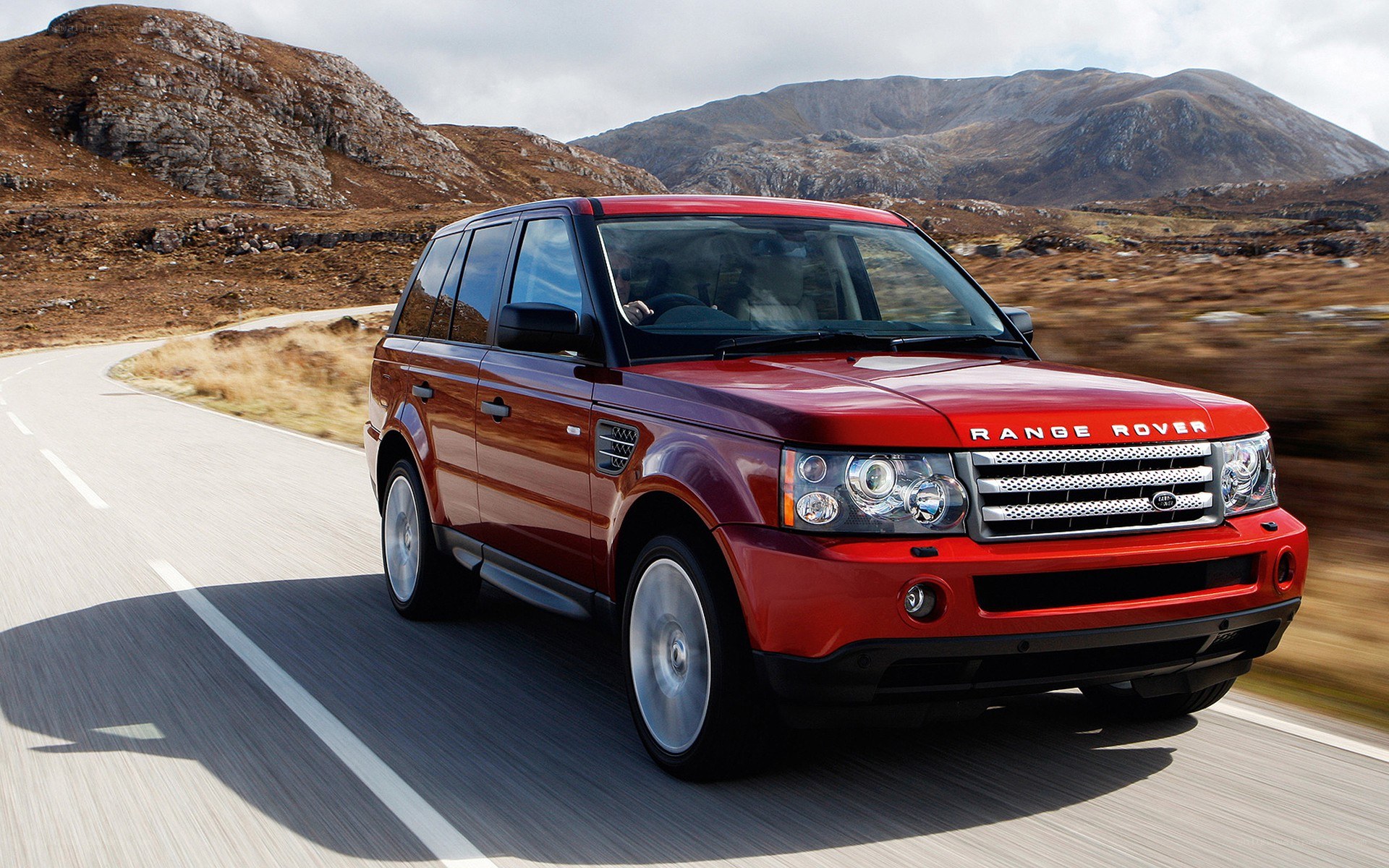 Red Range Rover driving on mountain road