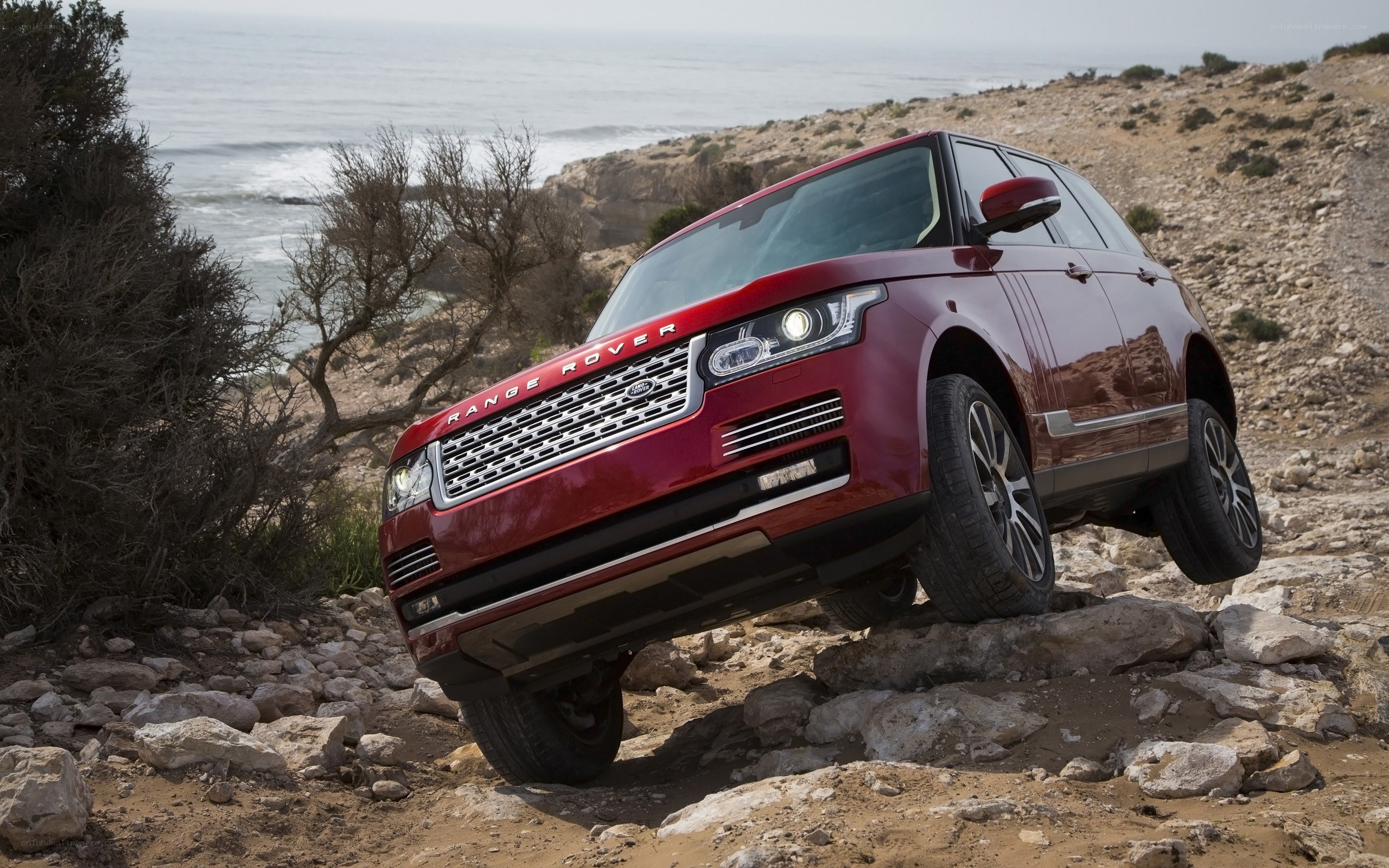 Red Range Rover on rocky coast